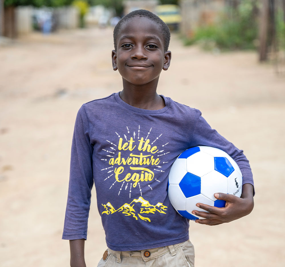 David smiling and holding a soccer ball after cleft surgery
